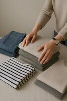 Organized Folded Clothes and Jeans on White Surface with Hands and Watch in Studio Light photo