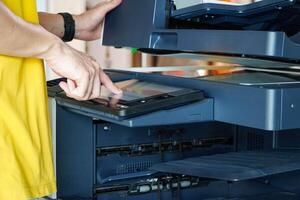 Men press the button of the copier. an copying paper from Photocopier. Men use printing machines. man using photocopier photo