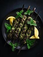 Grilled Green Herb Kebabs with Lemon and Mint on a Dark Plate. A close up overhead shot of delicious, flavorful food. photo