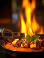 Grilled Paneer in Spicy Sauce with Flames in Background. A close up of delicious Indian cuisine. photo