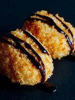 Close up of Two Crispy Fried Food Items Drizzled with Chocolate Sauce. photo