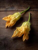 Two Fresh Squash Blossoms on Rustic Wooden Surface. photo