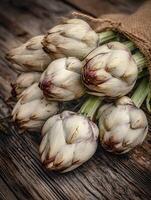 A Close Up of Fresh Artichokes in a Burlap Sack on Rustic Wood. photo