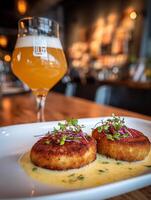 Gourmet Crab Cakes with Creamy Sauce and Beer in a Restaurant Setting. photo