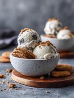 Delicious Cookies and Cream Ice Cream in a Bowl. A close up image of creamy ice cream scoops topped with cookie crumbs, served with fresh cookies. photo