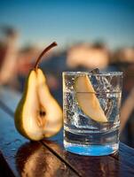 Refreshing Pear Cocktail on a Sunny Terrace. A close up image of a pear infused drink with ice, garnished with a pear slice, sitting on a wet wooden table outdoors. photo