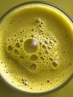 Close up of foamy yellow liquid in a glass, abstract bubbly texture. photo