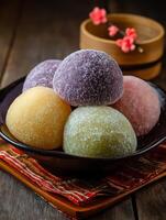 Colorful Mochi Sweets in a Dark Bowl, Close Up View. A delectable assortment of Japanese mochi, dusted with sugar, presented in a stylish bowl. photo