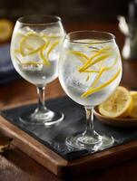 Two Gin and Tonics with Lemon Zest Garnishes on a Slate Serving Tray. photo