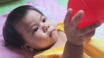 Baby is playing with a red rubber ball, Close-up, Learning development for newborns concept, Newborns laying down and touching rubber ball, activity toddler video