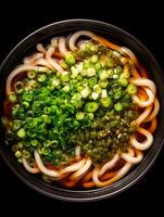 Delicious Udon Noodle Soup Close up of a bowl of udon noodles with green onions and a seaweed topping. photo