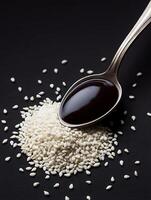 Close up of White Sesame Seeds and Dark Sauce on a Spoon. photo