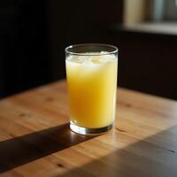 Refreshing Yellow Drink with Ice Cubes on Wooden Table in Sunlight photo