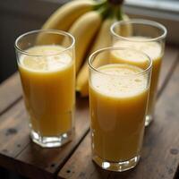 Banana Juice in Glasses with Fresh Bananas on a Wooden Table photo