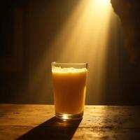 Glass of Orange Juice on Rustic Wood Table with Dramatic Lighting photo