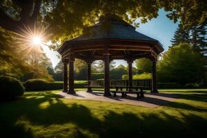 A gazebo in a park with the sun shining through the trees photo