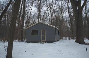 Small gray cabin nestled in a snowy forest. photo
