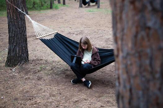 A girl in a hammock is working on a computer. Distant work. photo