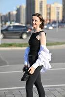 She is wearing a black top and a white shirt or jacket that is partially open. photo