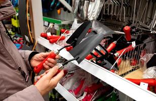 Person examining gardening tools in a hardware store. photo