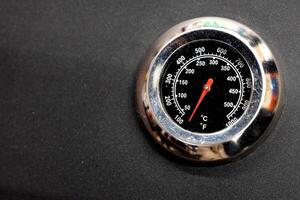 Close-up of thermometer with red needle on black surface. photo