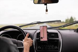 young traveler using a navigator on a mobile phone behind the wheel of a modern car . photo