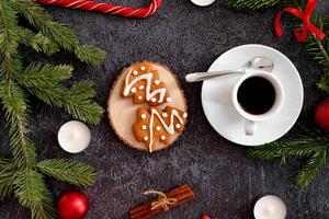 An aesthetic Christmas flat lay composition on a dark backdrop, highlighting heart-shaped candy canes, gingerbread trees, photo