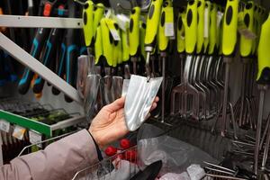 Person examining gardening tools in a hardware store. Handles product. photo