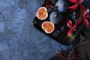 Ripe figs with red grape leaves. Autumn still life. Dark background photo