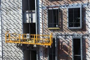 Construction site with hanging scaffold on brick building facade. photo