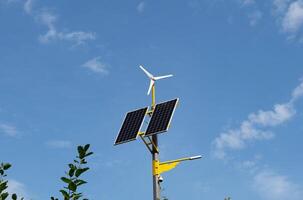 Solar panels and wind turbine against a blue sky. photo