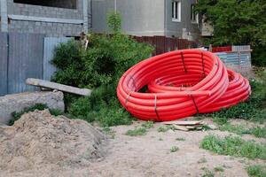 view looking down on large shiny black drain drainage sewer pipes stacked at a construction site with orange red net safety fencing photo