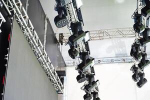 Stage lighting equipment hanging from trusses at an event venue. photo