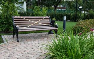 Park bench with caution tape in a garden setting. photo