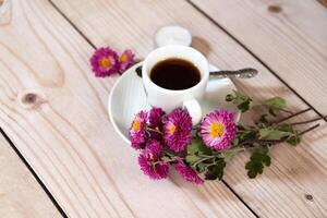 Overhead shot of an autumn-themed arrangement with a coffee cup as the central focus, surrounded by red macarons, flowers, leaves, acorns, and a candle. photo