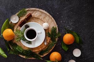 Overhead shot of a Christmas-themed arrangement with a cup of coffee as the central element, surrounded by gingerbread cookies, cinnamon, candy canes, candles, and pine sprigs. photo