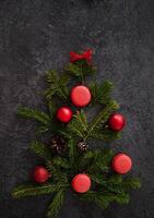 . A wintry flat lay with a coffee cup, gingerbread trees, cinnamon, candy canes, and pine sprigs, creating a visually appealing Christmas scene on a dark surface. photo