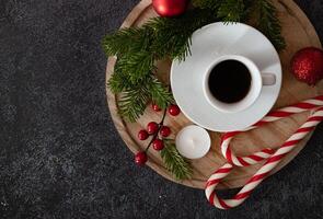 An overhead view of a Christmas-themed flat lay with a coffee cup, gingerbread cookies, cinnamon, candy canes, candles, and pine branches, beautifully arranged to create a warm, holiday atmosphere. photo