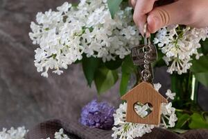 keys and keychain of a house against a background of lilac, a symbol of the family hearth and own home. Purchase of real estate. photo