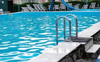 pool with metal ladder and lounge chairs around. photo