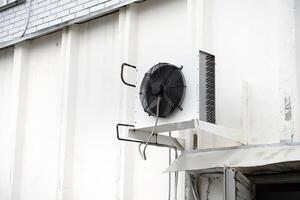 Industrial air conditioning unit mounted on white wall. Temperature control. photo