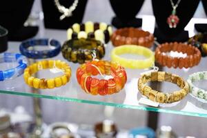 Assorted gemstone bracelets displayed on a glass shelf. photo