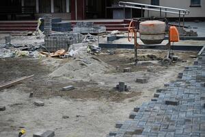 male hands measuring and leveling sand and cement tiles for precise pavement of the outside patio or sidewalk. Construction industry and renovation. photo