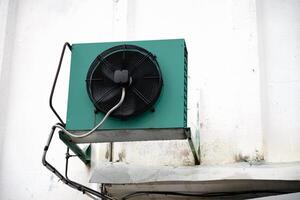 Industrial air conditioning unit mounted on white wall. photo