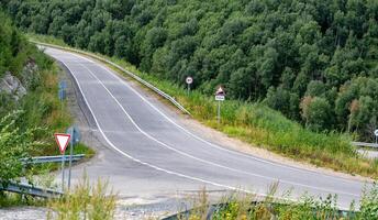 Curved road with traffic signs surrounded by lush greenery. photo