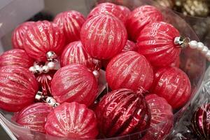 A section of a decorated Christmas tree is displayed, featuring pink and burgundy ornaments as well as a butterfly design. photo