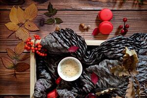 An aesthetic autumn flat lay composition, highlighting a cup of coffee, red macarons, purple flowers, leaves, acorns, and a candle on a textured background. photo