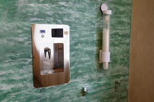 Close-up of water dispenser with a plastic cup filled with mineral water. photo