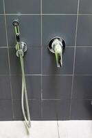 Close-up of a showerhead and faucet on tiled bathroom wall. photo