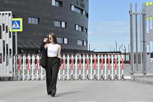Woman walking near a retractable gate in front of a modern building. photo